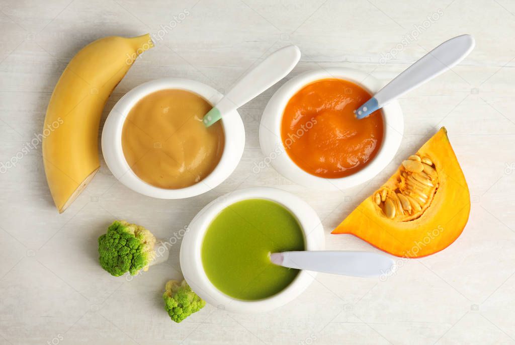 Bowls with different baby food on light background, flat lay