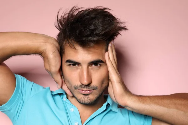 Young man with trendy hairstyle posing on color background