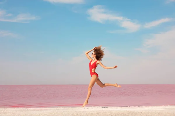 Piękna Kobieta Strój Kąpielowy Skoki Pobliżu Różowe Jezioro Słoneczny Dzień — Zdjęcie stockowe