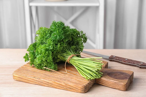 Wooden board with fresh green parsley on table