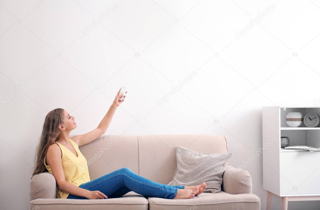 Young woman with air conditioner remote at home