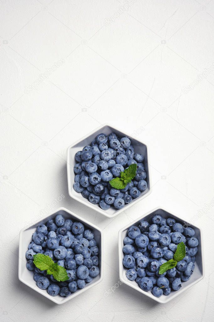 Flat lay composition with fresh blueberries, green leaves and space for text on table