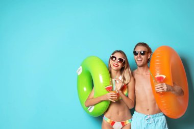 Mutlu genç çift beachwear şişme yüzük ve kokteyller üzerinde renk arka plan ile. Metin için yer