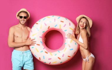 Mutlu genç çift renk arka plan üzerinde şişme yüzüklü beachwear içinde