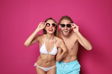Mutlu genç çift beachwear şişme yüzüklü ve renk arka plan üzerinde kokteyl