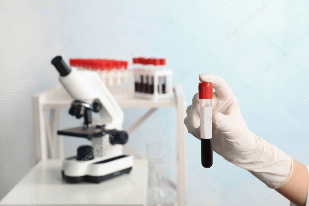 Doctor holding glass tube with blood in laboratory, closeup. Allergy test