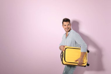 Bavul renk arka plan üzerinde olan genç adam. Metin için yer