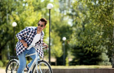 Yakışıklı genç hipster adam yakınındaki ahşap duvar açık havada bisiklet ile