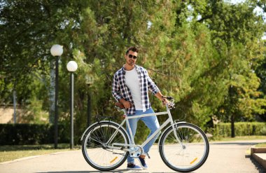 Yakışıklı genç hipster adam yakınındaki ahşap duvar açık havada bisiklet ile