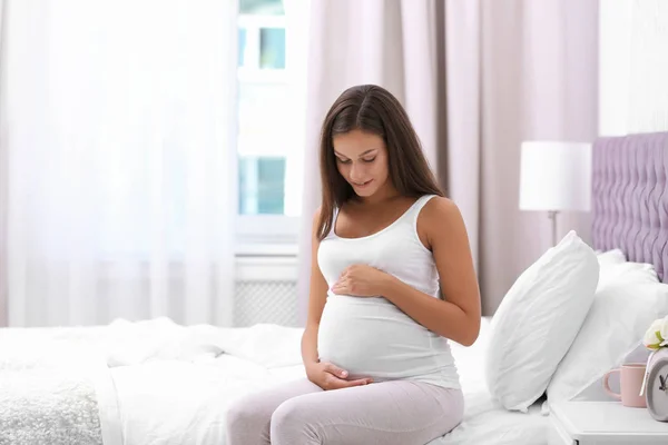 幸せな妊娠中の女性座っていますベッドに家 — ストック写真