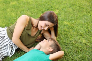 Park yeşil çimenlerin üzerinde şirin çocuk annesiyle. Mutlu bir aile