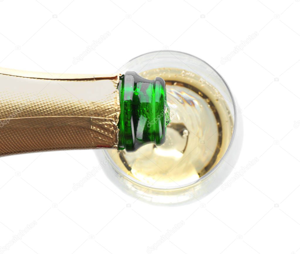 Pouring champagne from bottle into glass on white background, top view. Festive drink