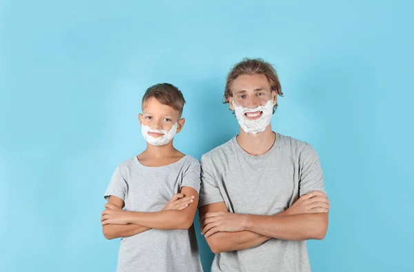 父亲和儿子与剃须泡沫在面孔反对颜色背景 — 图库照片