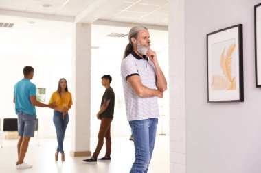 Sanat galerisindeki sergide bir bardak şampanyası olan genç bir kadın.