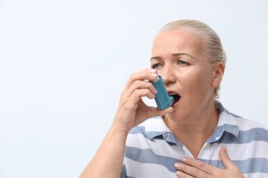 Beyaz arka plan üzerinde astım astım ilacı kullanan kadın