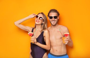 Beachwear renk arka plan üzerinde kokteyller ile mutlu genç çift