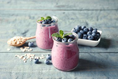 Lezzetli blueberry smoothie kavanoz, çilek ve yulaf ezmesi ahşap tablo