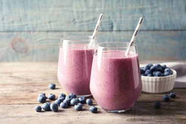 Gözlük ve ahşap masa üzerinde meyveleri lezzetli blueberry smoothie