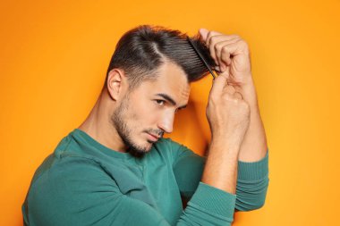 Renk arka plan üzerinde poz tarak ile genç adam. Son moda saç modeli