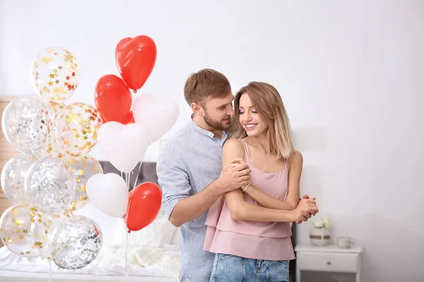 Young couple with air balloons in bedroom. Celebration of Saint Valentine\'s Day