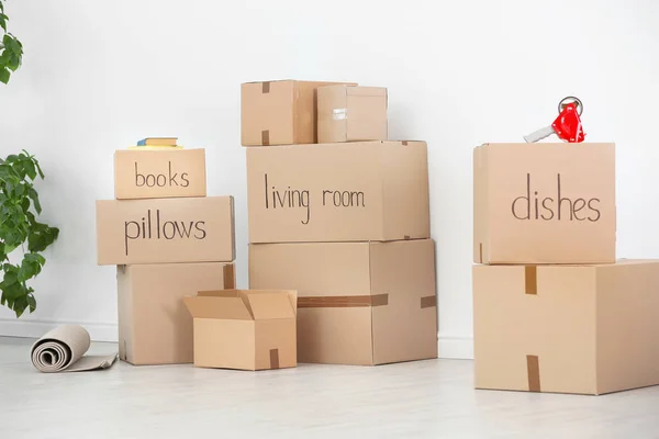 Cardboard boxes and household stuff near white wall indoors. Moving day