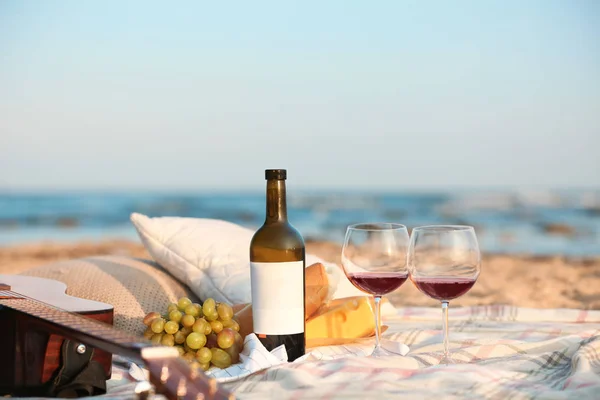 Blanket with food, wine and guitar on beach. Romantic picnic for couple