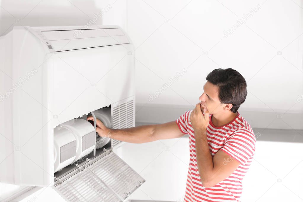 Young man fixing air conditioner at home