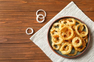 Ahşap masa, üstten görünüm ev yapımı çıtır çıtır kızarmış soğan halkaları. Metin için yer