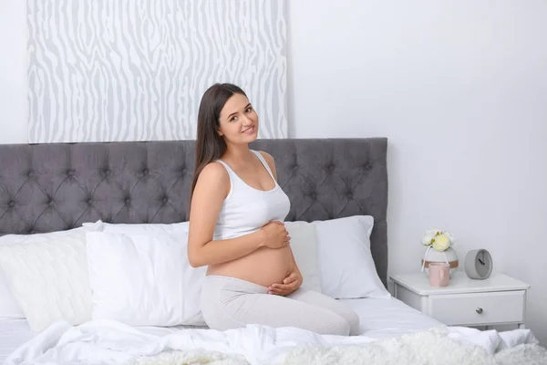 Młoda Piękna Kobieta Ciąży Siedząc Łóżku Dotykając Jej Brzuch Domu — Zdjęcie stockowe