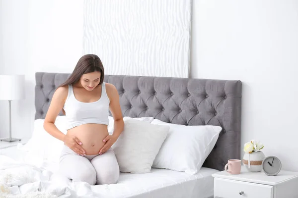 Młoda Piękna Kobieta Ciąży Siedząc Łóżku Dotykając Jej Brzuch Domu — Zdjęcie stockowe