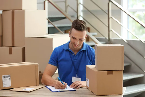 Joven Mensajero Trabajando Con Papeles Entre Paquetes Mesa Departamento Entrega —  Fotos de Stock