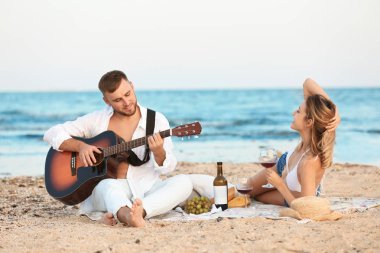 Kumsalda romantik akşam yemeği gitar ile genç çift