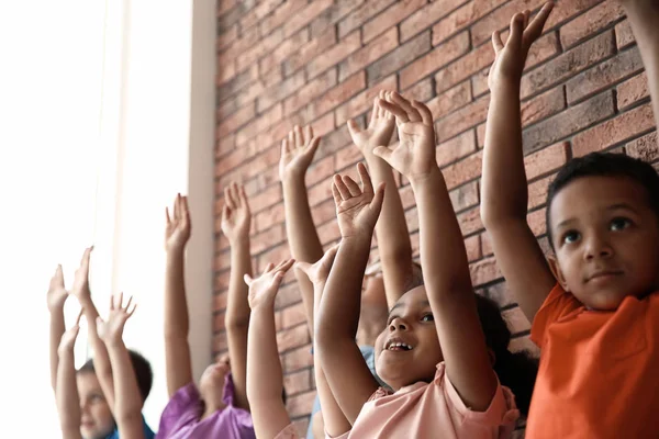 Little children raising hands together indoors. Unity concept