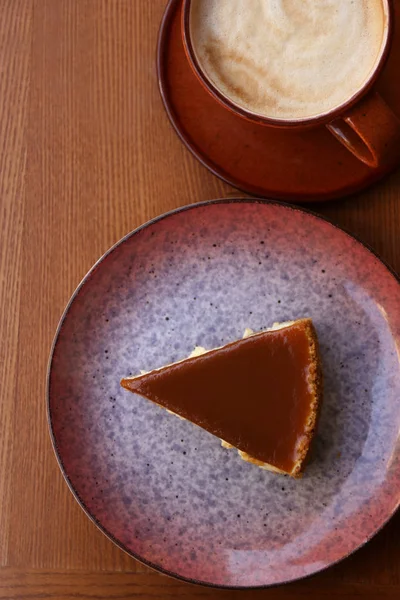 Cup of coffee and slice of cake on wooden table, top view