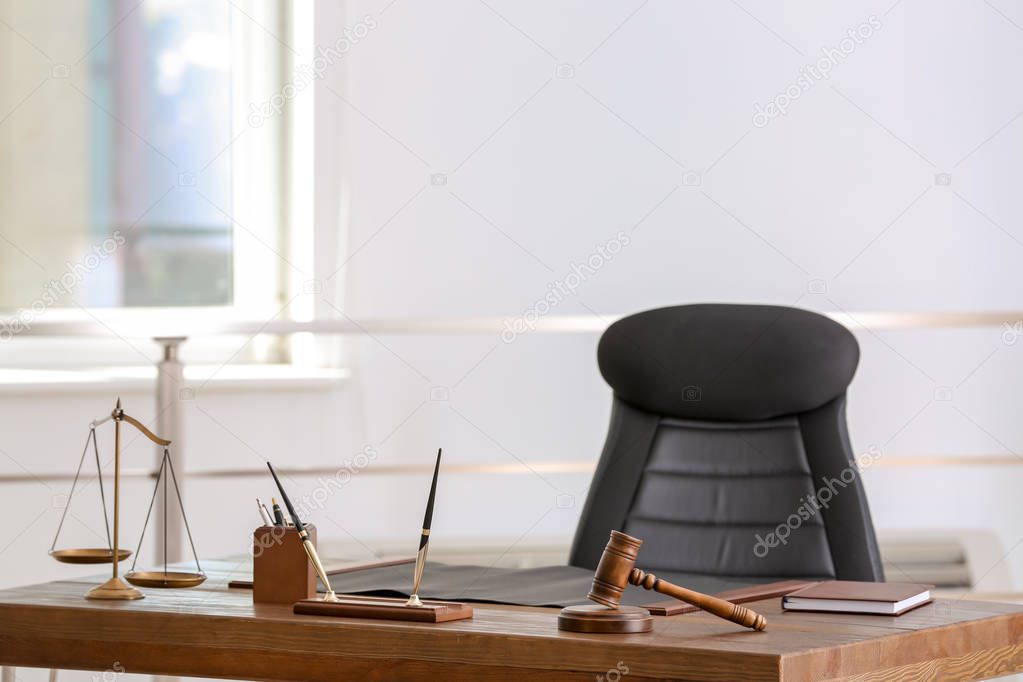 Table with scales of justice and judge gavel in lawyer's office