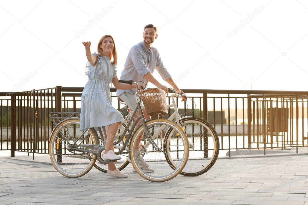 Happy couple riding bicycles outdoors on summer day