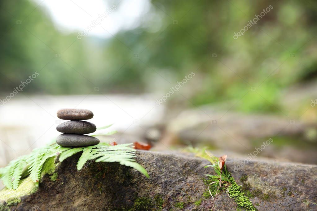 Balancing zen pebble stones outdoors against blurred background. Space for text