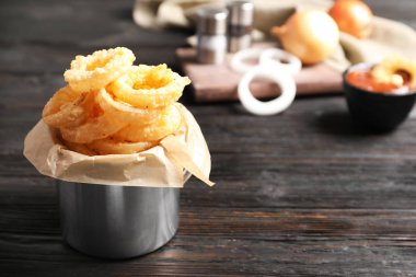 Dishware ahşap masa üzerinde ev yapımı çıtır çıtır kızarmış soğan halkası ile. Metin için yer