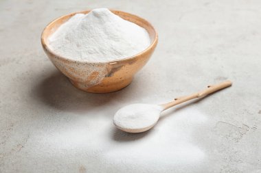 Kaşık ve gri arka plan üzerinde kabartma tozu ile kase