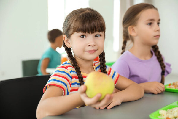 Children sitting at table and eating healthy food during break at school