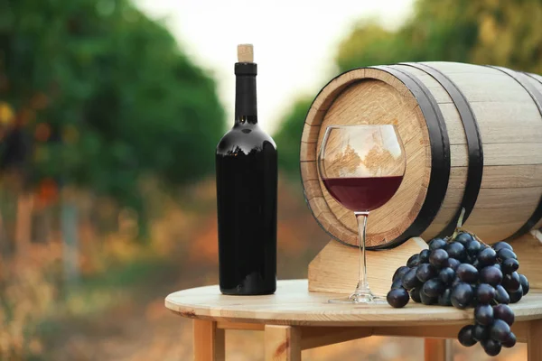 ワイン 樽とブドウ園で木製テーブルの上のガラスのボトル — ストック写真
