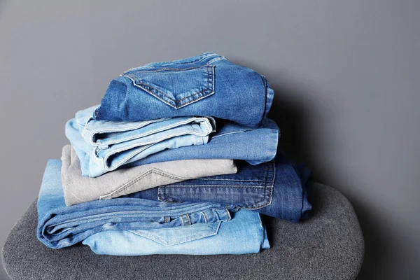 Stapel Van Verschillende Jeans Kruk Tegen Grijze Achtergrond — Stockfoto