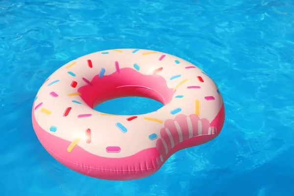 Inflatable ring floating in swimming pool on sunny day