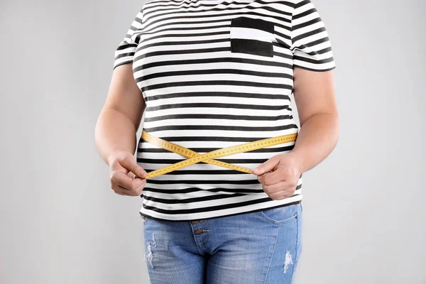 クローズ アップ 灰色の背景上のテープを測定する場合の太った女性 体重減少 — ストック写真