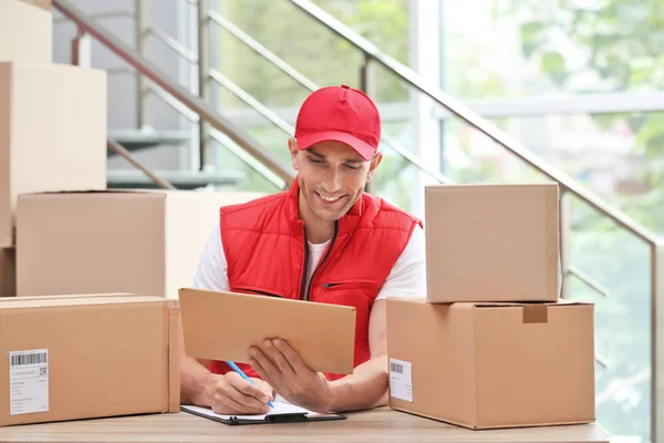 Joven Mensajero Trabajando Con Papeles Entre Paquetes Mesa Departamento Entrega — Foto de Stock