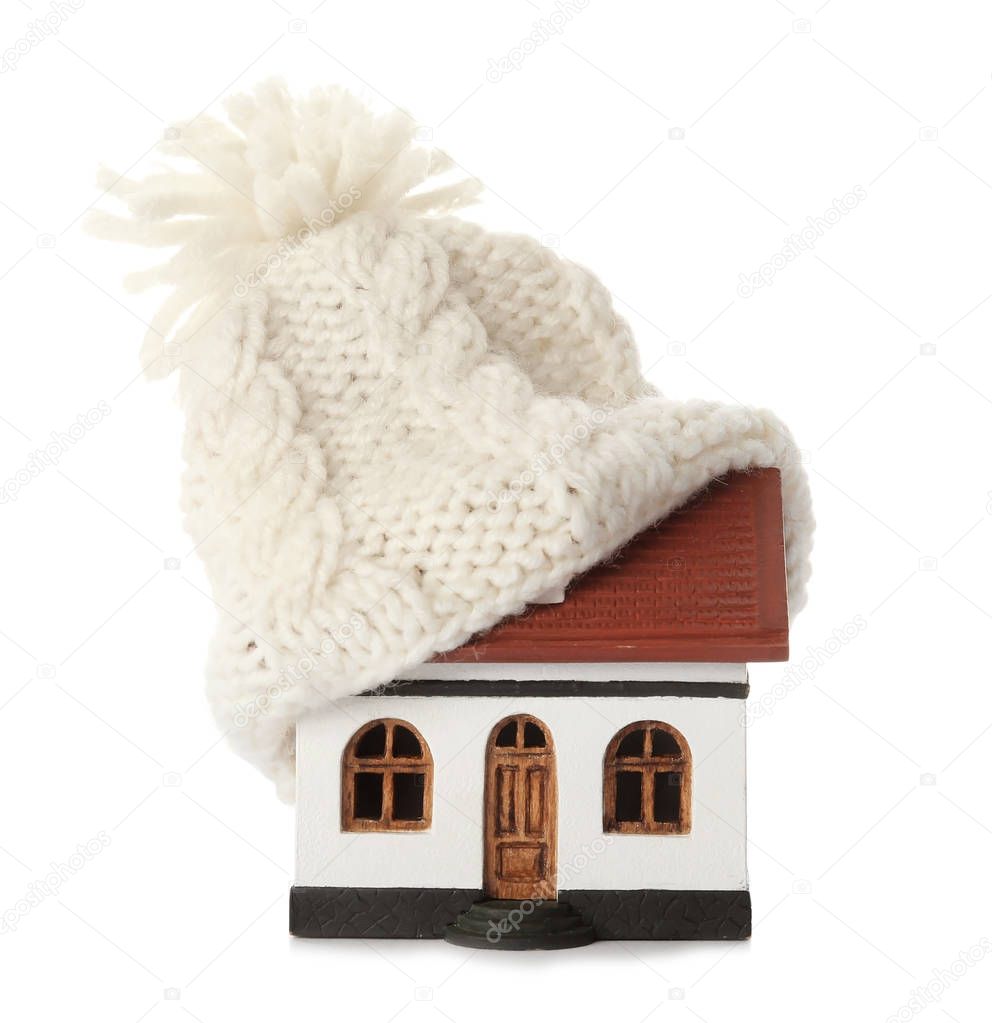 House model with knitted hat on roof against white background. Heating concept