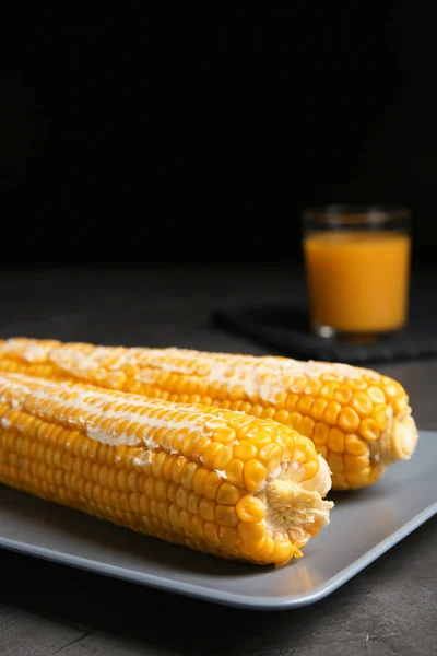 美味的煮玉米棒子与黄油在灰色表反对黑色背景 文本空间 — 图库照片