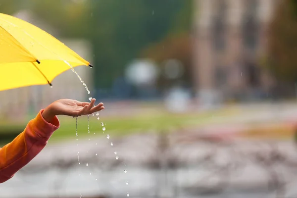 Woman with yellow umbrella under rain on street, closeup. Space for text