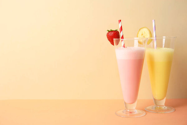 Glasses of tasty milk shakes and space for text on color background