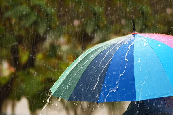 Person with bright umbrella under rain on street, closeup